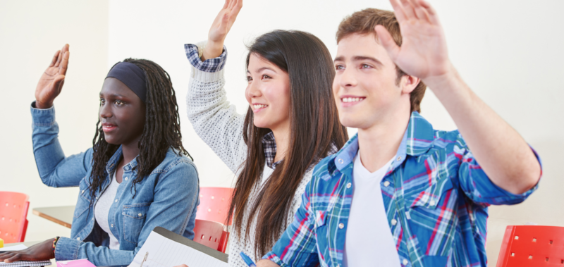 Students with their hands up in class